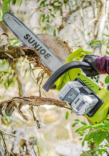 Sun Joe 48-volt 16-inch Cordless Chain Saw Kit cutting a branch off of a tree.